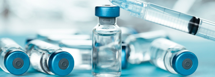 Injectable medicine or drug vials and syringe close up in blue tones