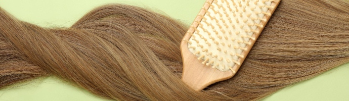 Female hair with hairbrush on green background